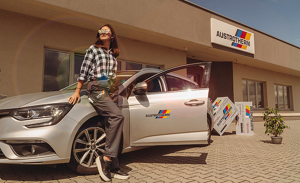 modelka pokazuje spodnie opierając się o auto